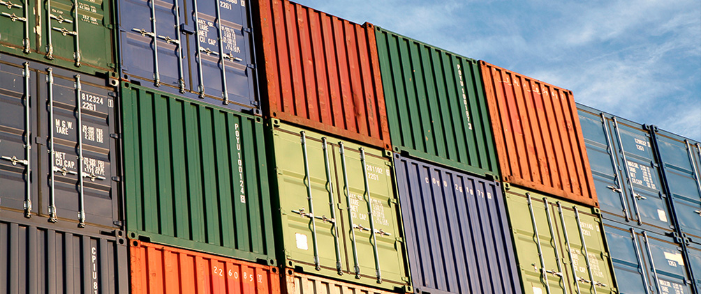 Stacked shipping containers representing industrial real estate, supply chain resiliency and higher energy cost impacts on logistics demand.