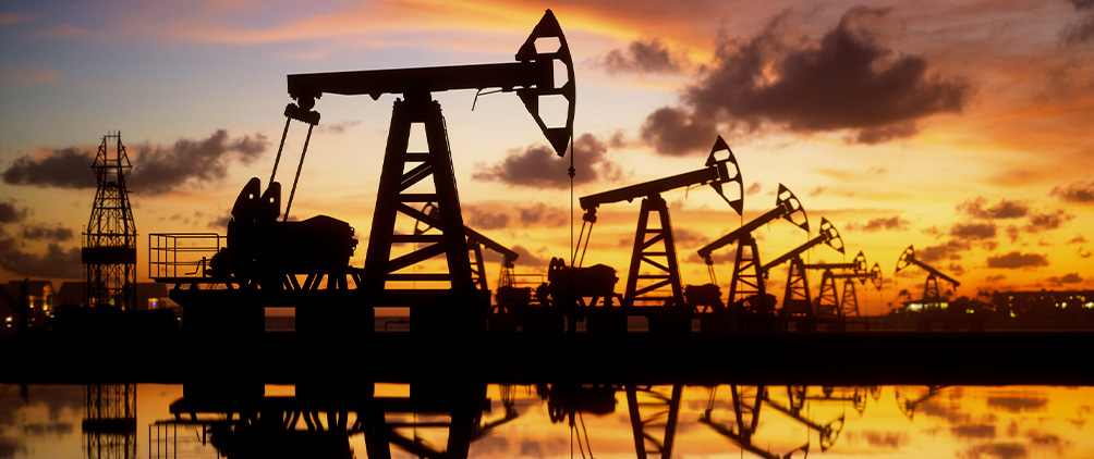 Oil pumpjacks silhouetted at sunset representing emerging market oil credit, energy markets and commodity price volatility.